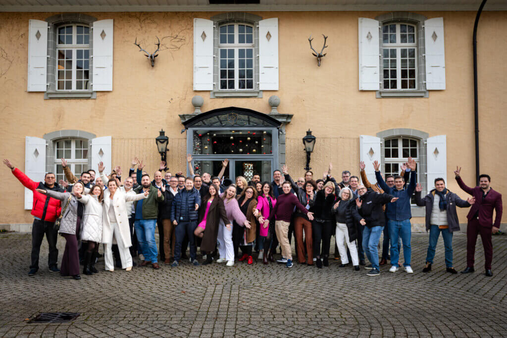 Un grand groupe de participants pose devant un bâtiment lors d’un événement professionnel.