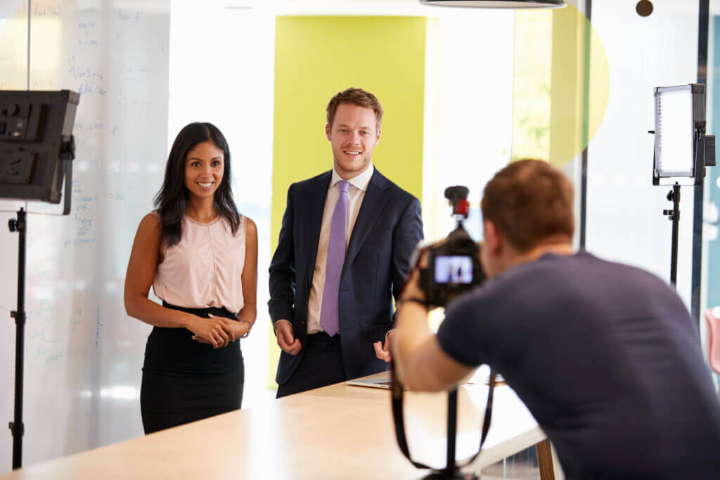 Photographe professionnel réalisant un portrait de deux collaborateurs dans un bureau avec éclairage de studio