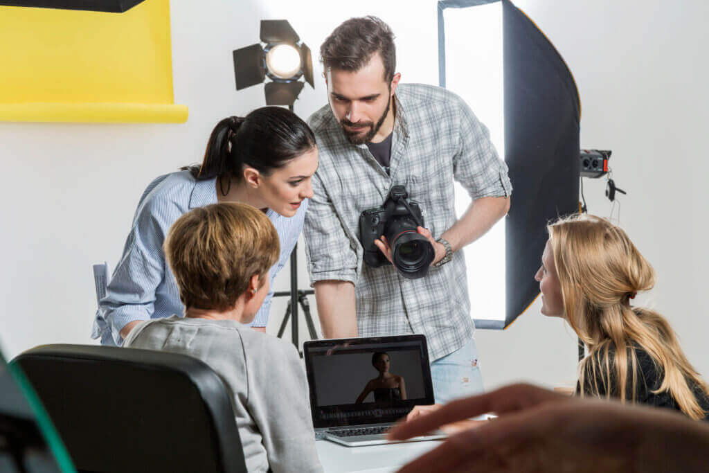 Équipe de production photo et vidéo réunie autour d'un ordinateur portable pour sélectionner les images d'un événement