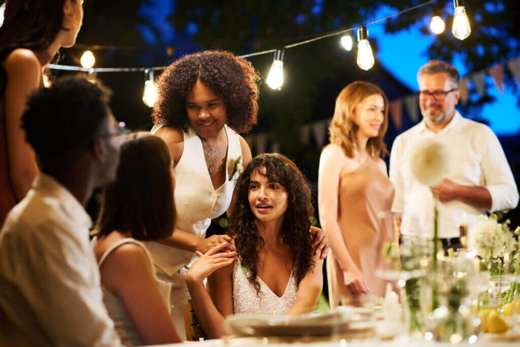 Convives réunis autour d'une table lors d'une soirée événementielle en extérieur avec guirlandes lumineuses et ambiance chaleureuse
